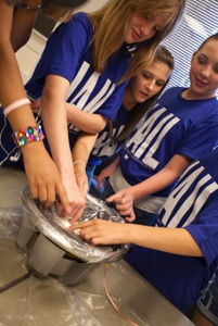 Students playing with Oobleck located on top of a speaker.